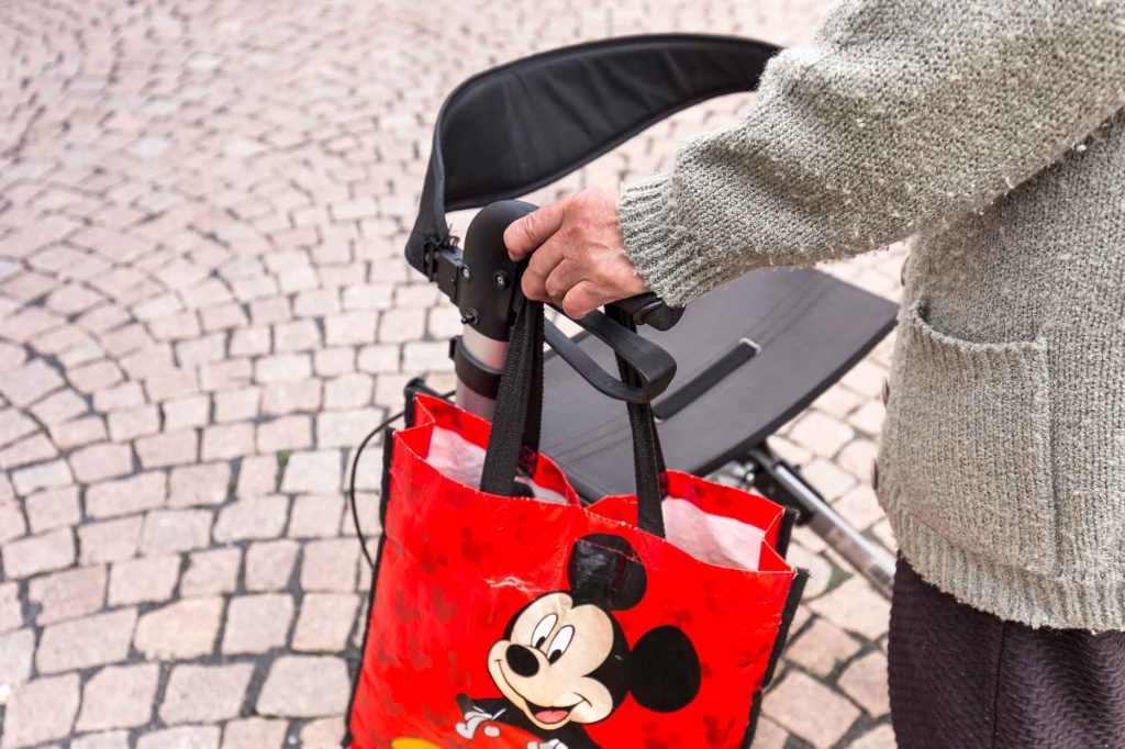 Frau mit Rollator und Mickey-Maus-Tasche