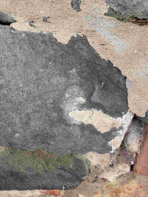 Eine vom Wetter verwaschene Mauer. Doch was blickt da- ein Monster?